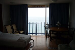 Ein Hotelzimmer mit Bett, Esstisch, Stühlen und Meerblick vom Balkon aus.