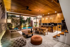 A modern interior with a dining area, kitchen, and a view of a pool. - Nusantara Loft Ambon (Pererenan)