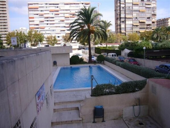 A rooftop swimming pool with steps leading down, surrounded by high-rise buildings and palm trees. - Torre Levante 6B in Benidorm (Benidorm)