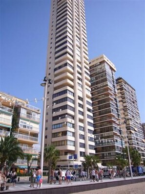 A tall, multi-story building with balconies, located near a busy pedestrian area with palm trees. - Torre Levante 6B in Benidorm (Benidorm)