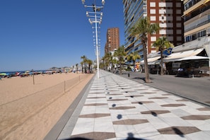 Eine Uferpromenade mit einem gemusterten Gehweg, Palmen und Gebäuden mit Balkonen.