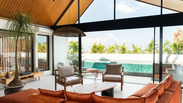 A modern interior with a large window, a pool view, and a wooden ceiling. - Makia Penthouse in Canggu (Canggu)