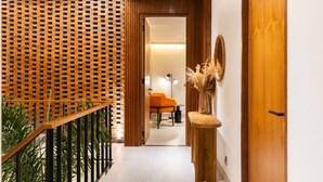 A hallway with a wooden wall, a door, and a small table with a vase. - Makia Penthouse in Canggu (Canggu)