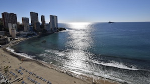 Paisagem costeira urbana com arranha-céus, praia e oceano.