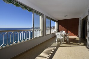 A balcony with a view of the sea, a table with chairs, and a railing. - Torre Principado 20E (Benidorm)