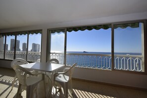 A balcony with a table and chairs, a view of the sea, and a cityscape in the background. - Torre Principado 20E (Benidorm)
