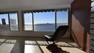 A balcony with a view of the sea, a chair, and a railing.
