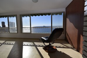 Un balcón con vista al mar, una silla y una barandilla.