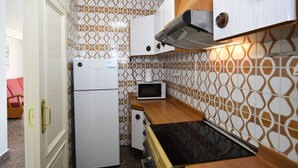 Cozinha compacta com geladeira, micro-ondas, fogão e bancada de madeira.