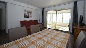 Quarto de hotel com cama, sofá, escrivaninha e varanda com vista.