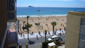 Una playa con gente, palmeras y una camioneta blanca.