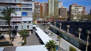 Un edificio de varios pisos con balcones, zona de estacionamiento techada y paseos peatonales.