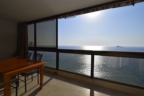 Ein Balkon mit Meerblick, einem Esstisch und Stühlen.