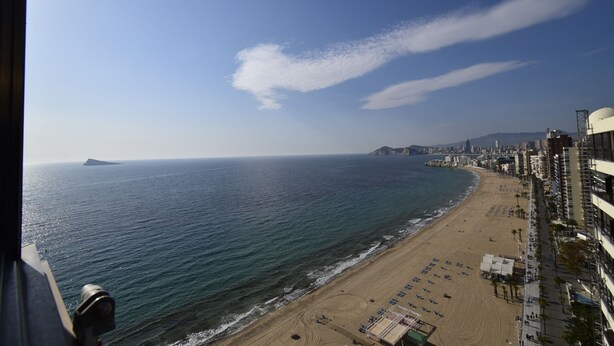 Paesaggio costiero con spiaggia, edifici e cielo sereno.
