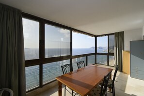 Ein Zimmer mit einem großen Fenster, einem Holztisch und Stühlen.