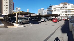 A parking area with multiple cars, a covered structure, and buildings in the background. - Cachirulo 4A in Benidorm (Benidorm)