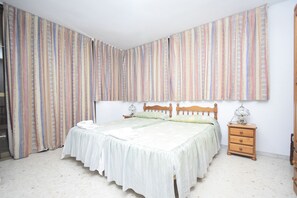 Un dormitorio con cama, mesita de noche y cortinas.