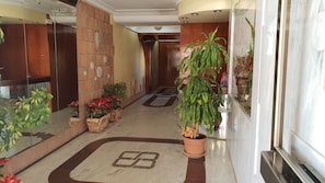 A hotel corridor with wooden paneling, potted plants, and a marble floor with a geometric pattern. - Cachirulo 4A in Benidorm (Benidorm)