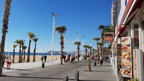 A coastal promenade with palm trees, a beach in the background, and a restaurant with food menu signs. - Cachirulo 4C in Benidorm (Benidorm)