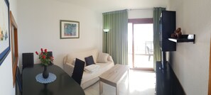 A room with a dining table, a sofa, a TV on a stand, and a window with curtains. - Cachirulo 4C in Benidorm (Benidorm)