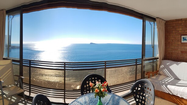 A balcony with a view of the sea, a table with a vase of flowers, and a sofa. - Cachirulo 4C in Benidorm (Benidorm)