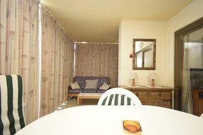 Ein Zimmer mit einer Couch, einem Esstisch, einem Stuhl, einem Spiegel und einer Lampe.
