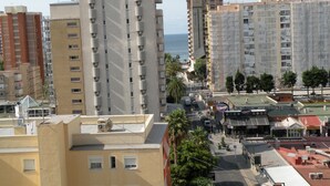 A cityscape with high-rise buildings, a street with parked cars, and a view of the sea. - Principado Centro 7 A (Benidorm)