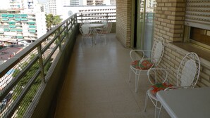 A balcony with a table and chairs, a view of the cityscape, and a brick wall. - Principado Centro 7 A (Benidorm)