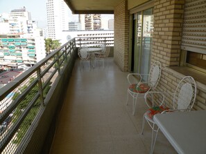 A balcony with a table and chairs, a view of the cityscape, and a brick wall. - Principado Centro 7 A (Benidorm)