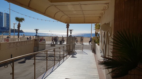 Ein Balkon mit Blick auf den Strand, einem Metallgeländer und einer Palme.