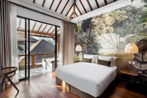 Ein Schlafzimmer mit einem großen Bett, Blick ins Freie, einer Wandmalerei von Pflanzen und einem Balkon mit einem Stuhl.