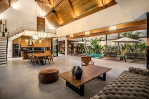 Ein großzügiger Wohnbereich mit Esstisch, Sofas und Blick auf einen Pool.