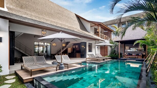 A modern pool area with lounge chairs and umbrellas, a staircase, and a covered seating area. - Villa Nusantara 3 in Pererenan (Pererenan)