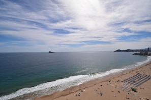 A beach with a clear sky, calm sea, and a sandy shore with umbrellas and chairs. - LOS Gemelos 15E in Benidorm (Benidorm)