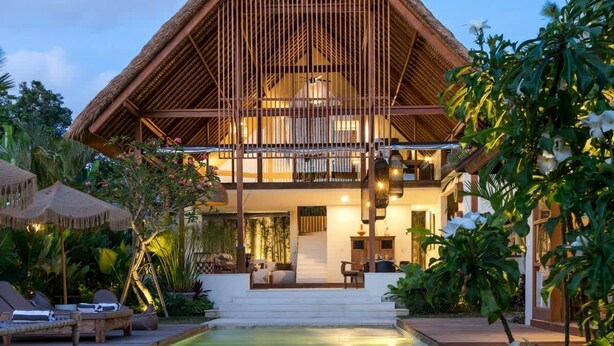 Ein Resort mit Pool, Liegebereich und einem Gebäude mit einem Strohdach.