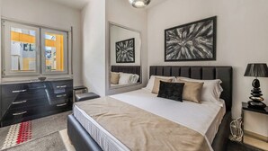 Un dormitorio moderno con una cama, mesitas de noche, un aparador, un espejo y obras de arte en las paredes.