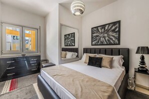 Ein modernes Schlafzimmer mit einem Bett, Nachttischen, einer Kommode, einem Spiegel und Bildern an der Wand.