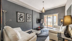 Una sala de estar moderna con un sofá, una mesa de centro, un televisor y obras de arte en la pared.