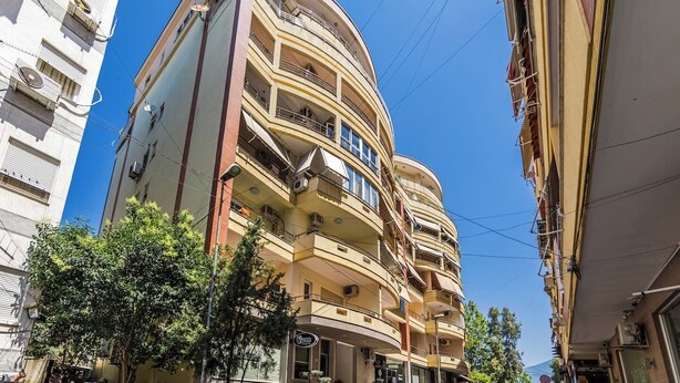 Un edificio de varios pisos con balcones, una fachada visible y cielo despejado.