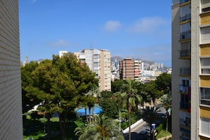 Ein Hochhaus mit Balkonen, Blick auf eine Stadtlandschaft und ein Park mit Bäumen.