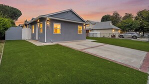 Ett bostadshus med en välskött gräsmatta, en uppfart och en inhägnad trädgård.