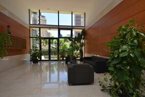 A lobby with a large glass window, a seating area, and potted plants. - Torre Ipanema 9D in Benidorm (Benidorm)