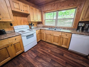 A kitchen with wooden cabinets, a white stove, and a dishwasher.