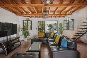 A living room with a sectional sofa, a flat-screen TV, a coffee table, and a staircase. - Spacious 12-bedroom resort with AC in excellent Cabarete (Cabarete)