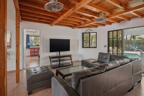 A modern living room with a wooden ceiling, a television, leather sofas, and a glass coffee table. - Spacious 12-bedroom resort with AC in excellent Cabarete (Cabarete)