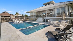 A swimming pool with lounge chairs, a covered patio, and a large house with multiple levels and balconies. - Luxury Waterfront Retreat with Gulf Access, Pool & Sunset Views (Bonita Springs)