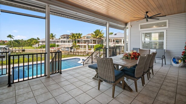 A covered patio with a pool, outdoor furniture, and a view of neighboring houses. - Luxury Waterfront Retreat with Gulf Access, Pool & Sunset Views (Bonita Springs)