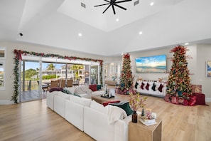 Ein geräumiges Wohnzimmer mit einem weißen Sofa, zwei Weihnachtsbäumen und einem Balkon mit Blick.
