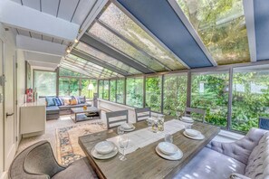 Ein modernes Interieur mit Essbereich, Sitzgelegenheiten und großen Fenstern.