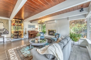 A spacious living room with a fireplace, a coffee table, and a sofa. - Modern Mid-Century Home - Solarium, Deck and Jacuzzi (North Vancouver)